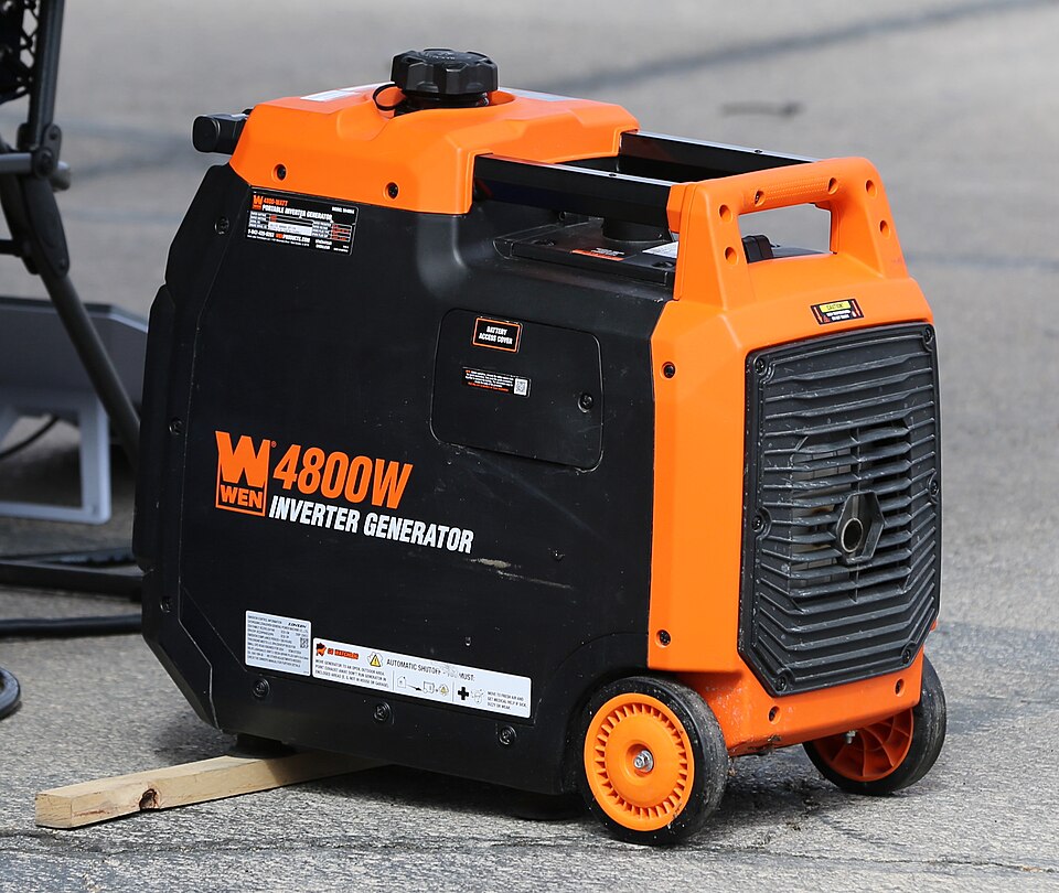 An orange and black WEN 4800 inverter generator with wheels, sitting on pavement, for storm prep in Panama City, FL